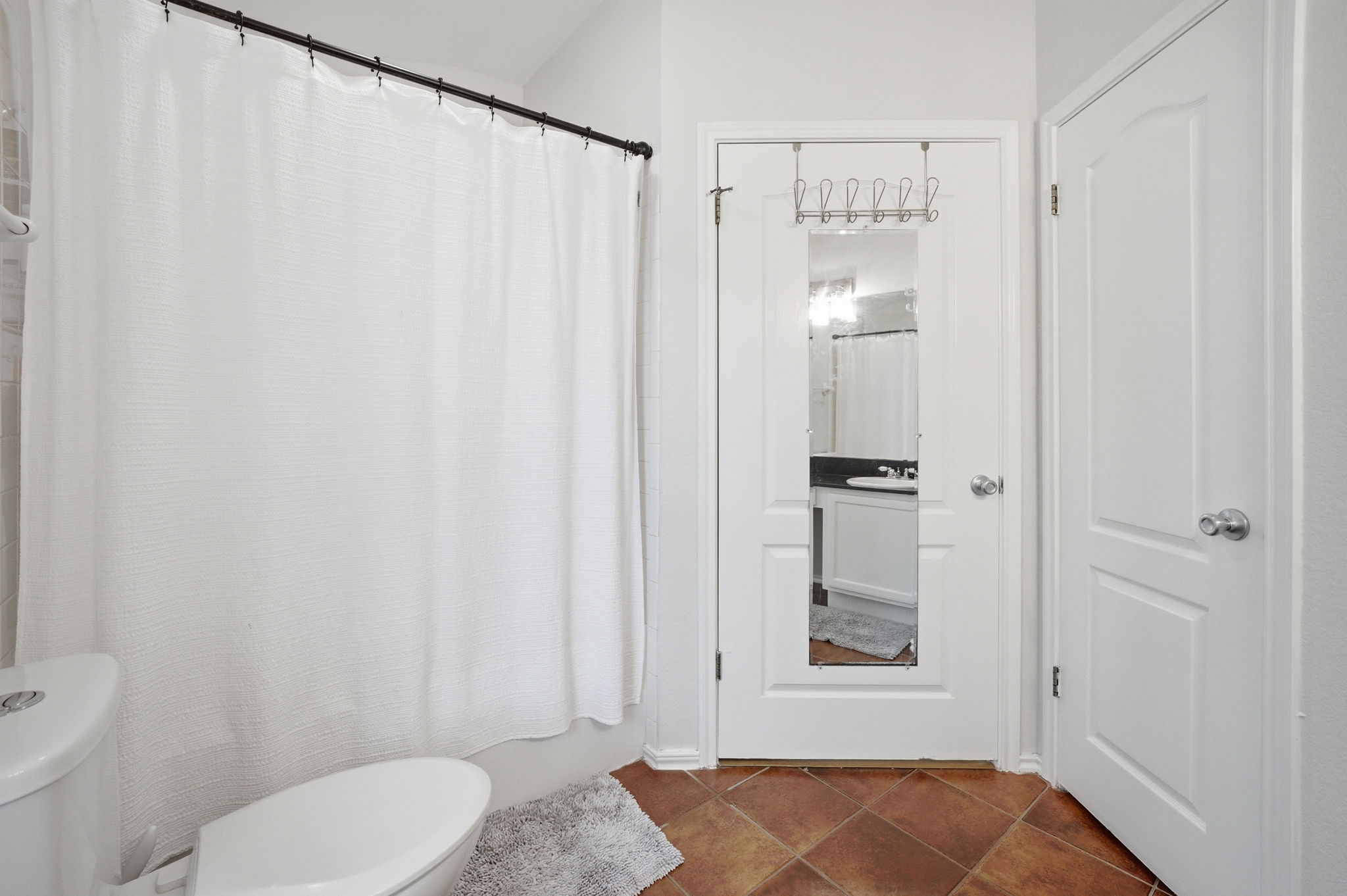 9024 Heiden Lane Austin, TX 78749 - Photo 18 of 28 Bathroom featuring diagonal tile flooring, a white toilet, and a white paneled door
