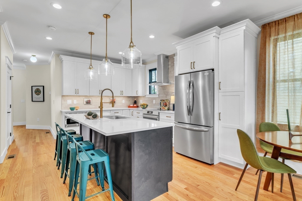 a kitchen with stainless steel appliances granite countertop a sink a stove a refrigerator and island with wooden floor