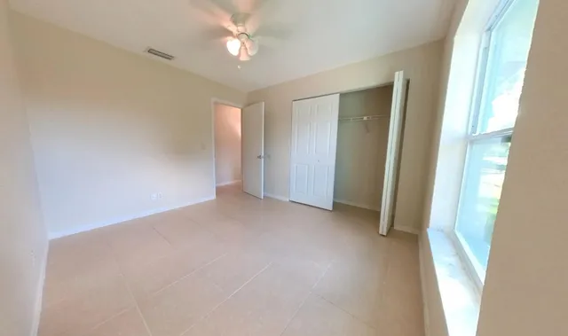 a view of a big room with windows and chandelier fan