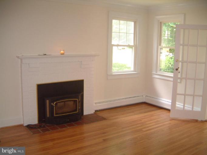 13919 Overton Lane Silver Spring, MD 20904 - Photo 5 of 16 an empty room with wooden floor a fireplace and windows