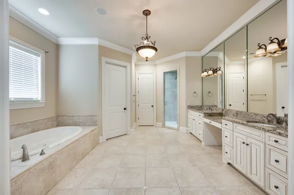 a spacious bathroom with a granite countertop tub sink shower and mirror