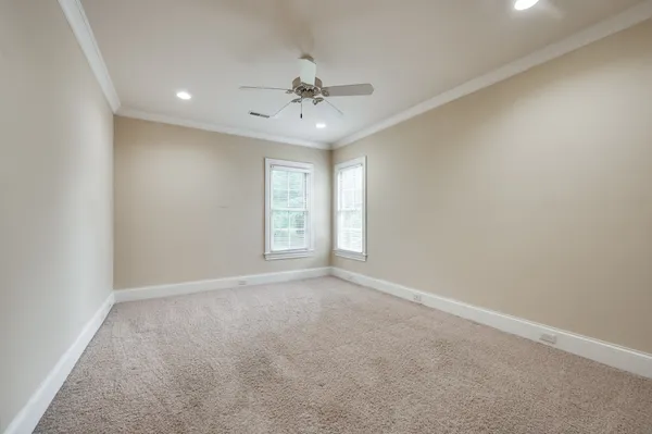 an empty room with windows and ceiling fan