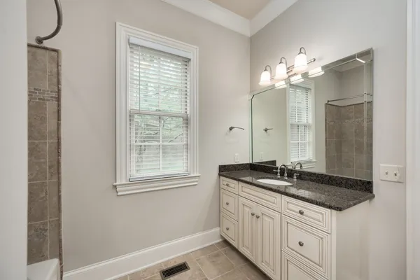 a bathroom with a granite countertop sink a large mirror and a shower
