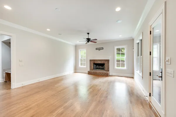 an empty room with wooden floor fireplace and windows