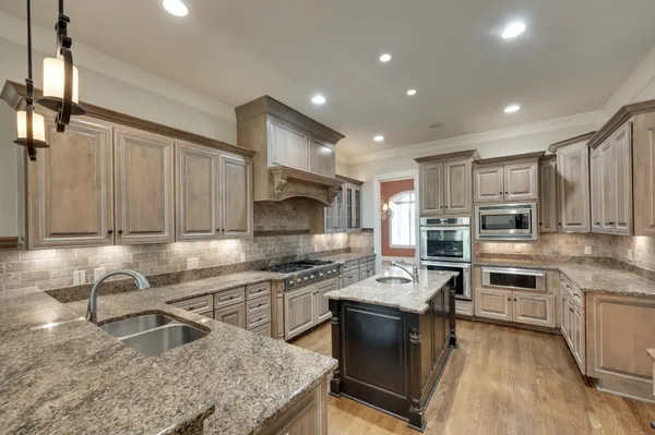 a kitchen with kitchen island granite countertop a sink counter top space appliances and cabinets