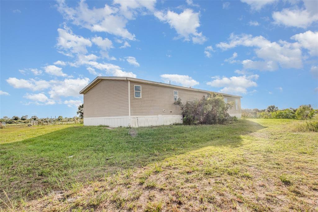 16423 Northwest 262nd Street Okeechobee, FL 34972 - Photo 29 of 30 a backyard of a house with lots of green space and mountain view in the background