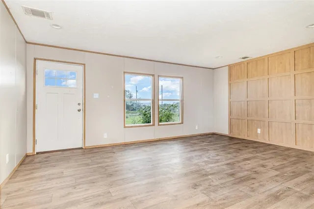 an empty room with wooden floor and windows