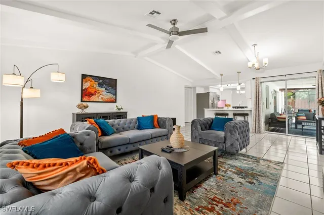 a living room with furniture kitchen view and a chandelier