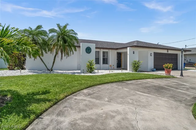 a view of a white house with a big yard and palm trees