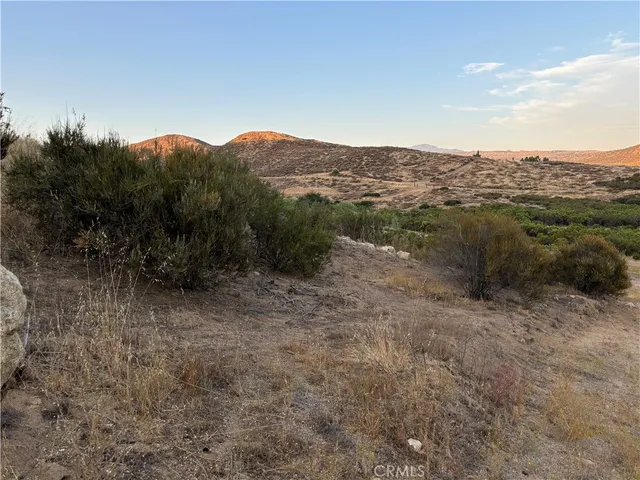 a view of a dry field with mountains in the background