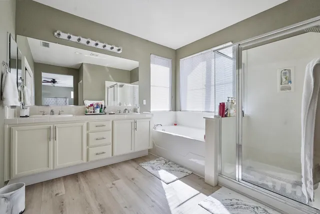 a spacious bathroom with a double vanity sink a mirror and a bathtub