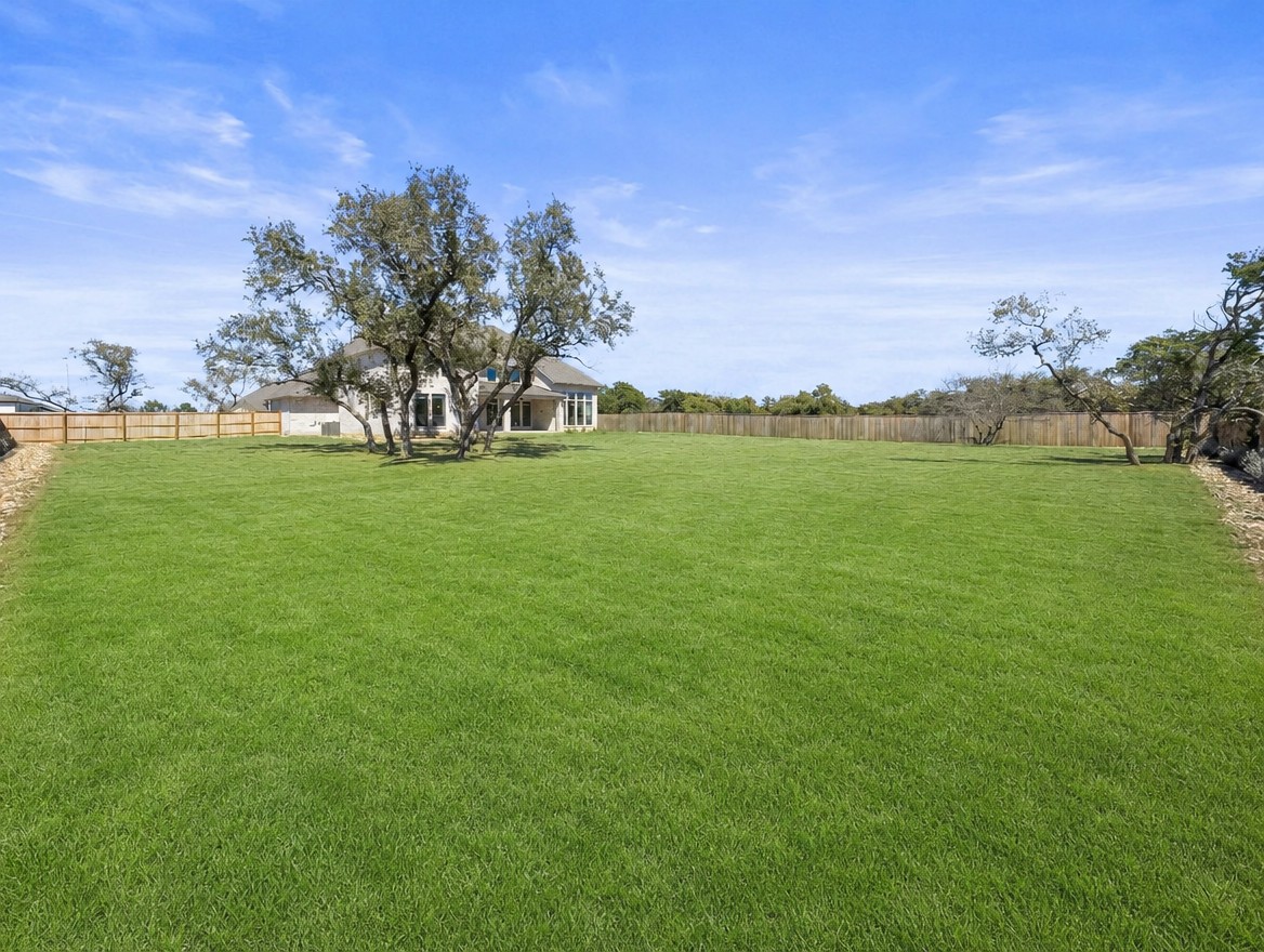 1440 Riva Ridge Drive Leander, TX 78641 - Photo 33 of 37 An expansive green yard extends toward a charming single-story home nestled amongst mature trees.