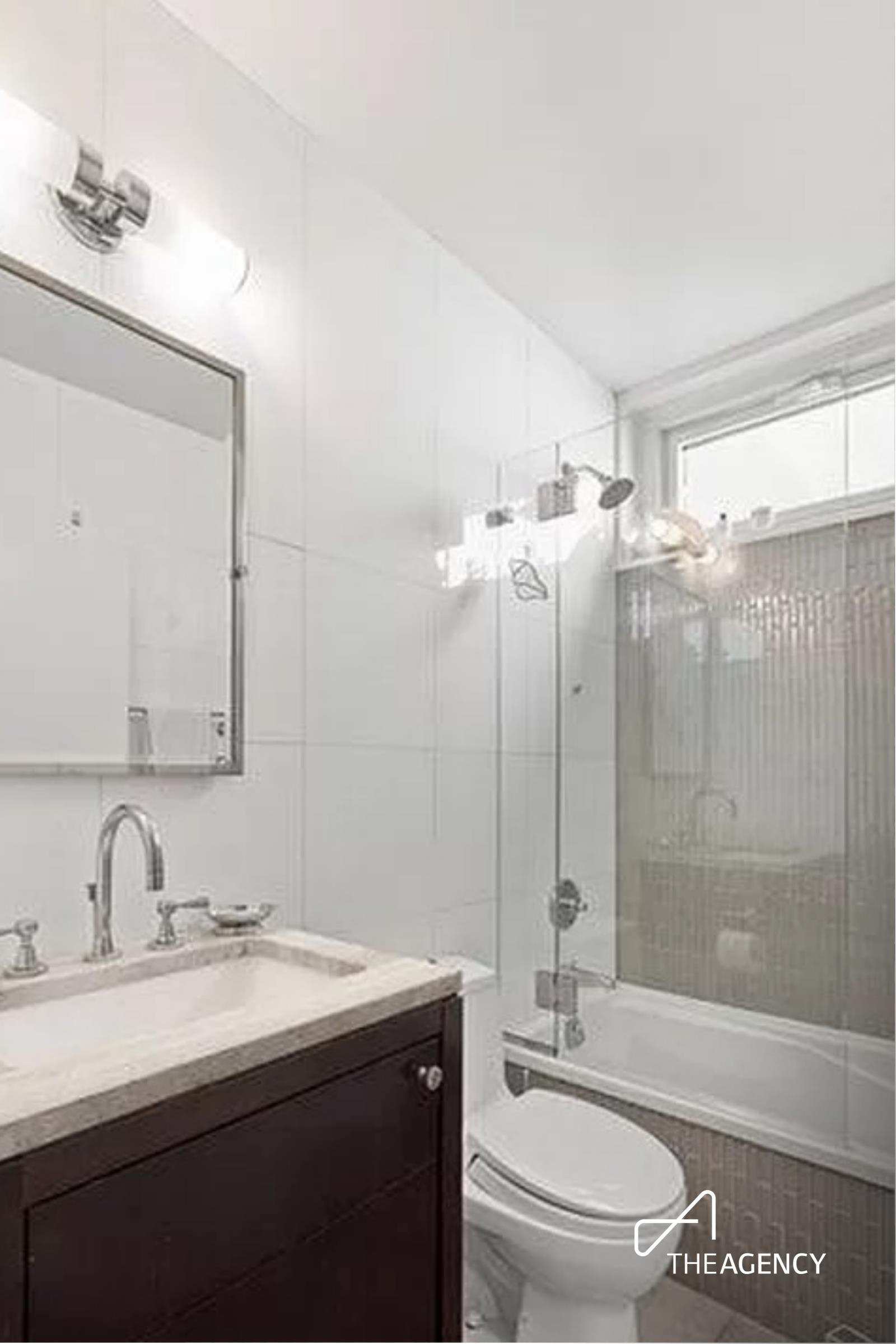 212 East 47th Street, Unit 34C Manhattan, NY 10017 - Photo 6 of 9 a bathroom with a sink a toilet and shower