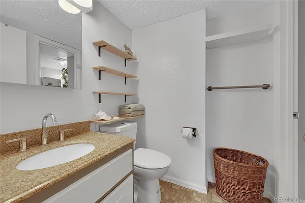 a bathroom with a granite countertop sink a toilet and a mirror