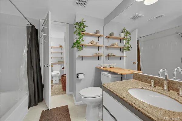 a bathroom with a granite countertop toilet sink and shower