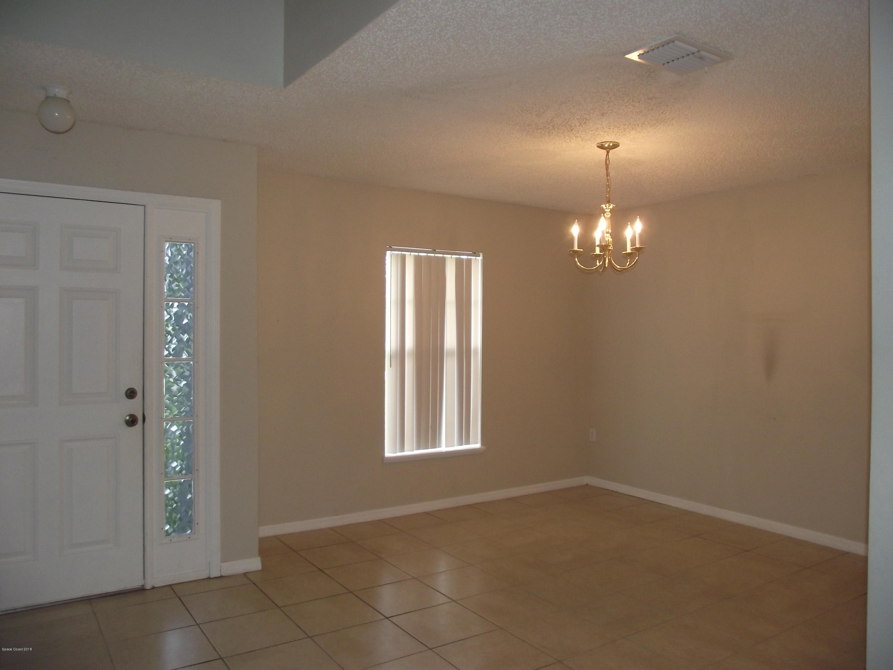1006 Ray Road Southeast Palm Bay, FL 32909 - Photo 3 of 21 an empty room with chandelier fan and windows
