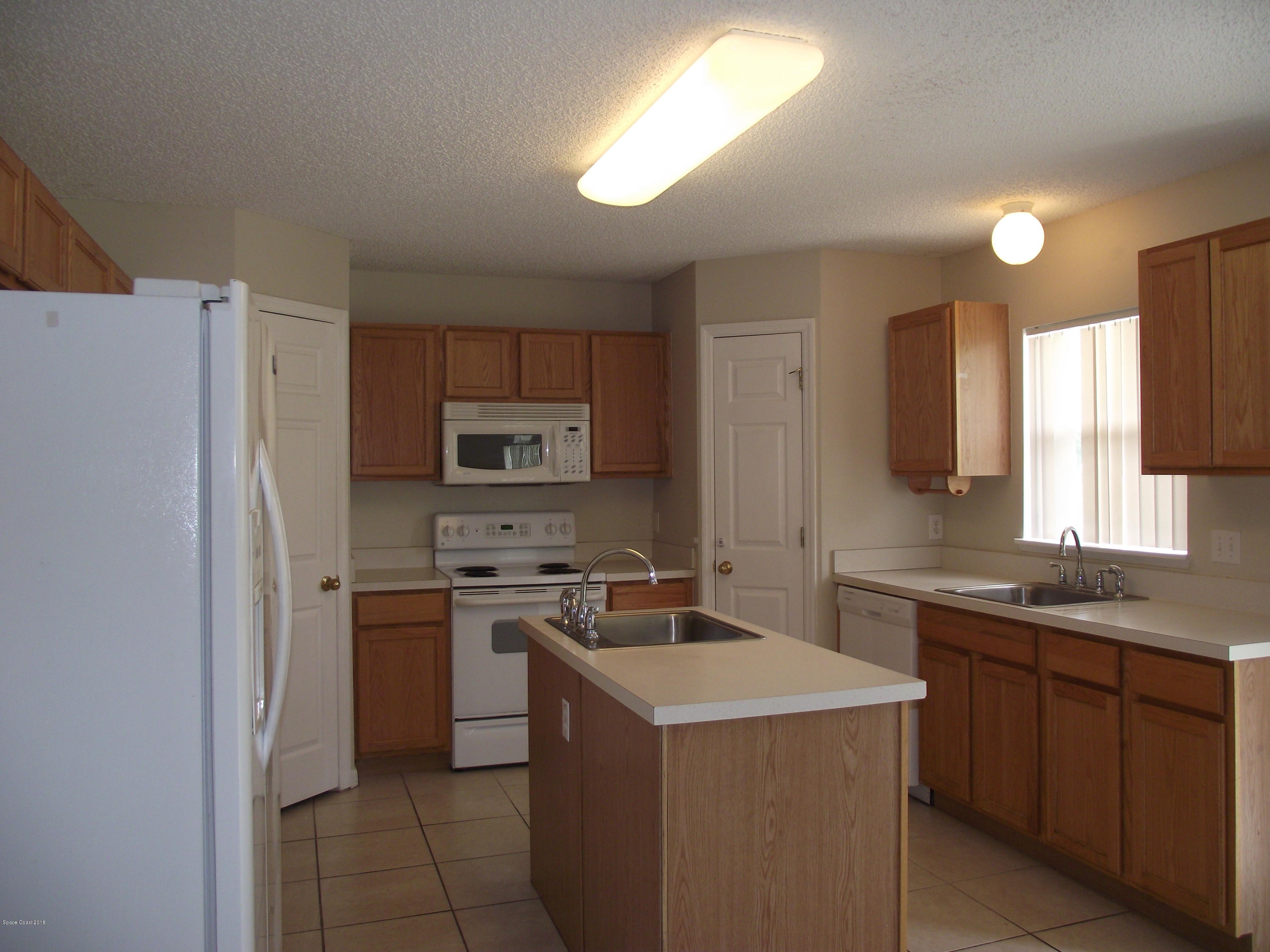 1006 Ray Road Southeast Palm Bay, FL 32909 - Photo 6 of 21 a kitchen with a sink stove and refrigerator