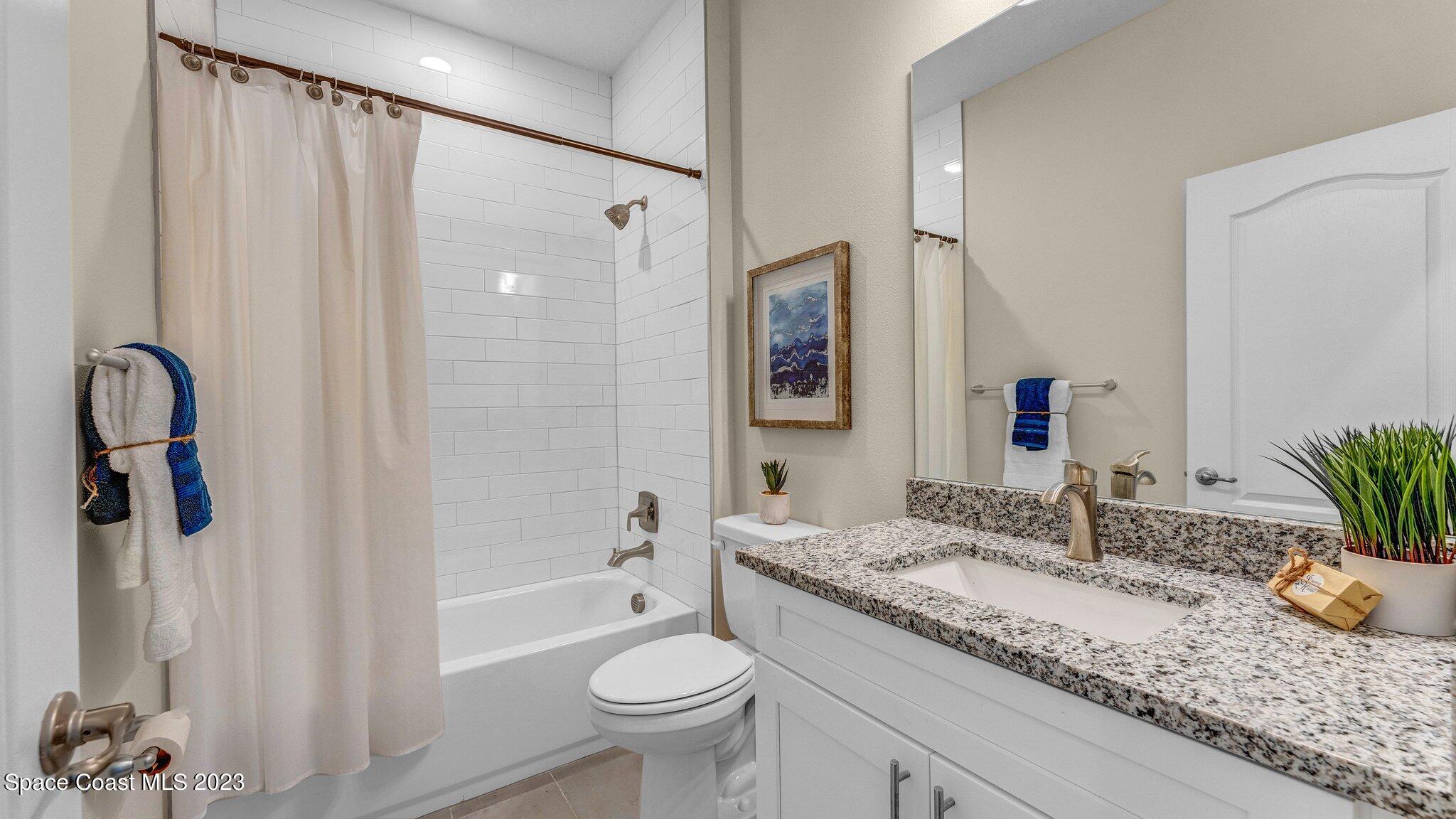 491 Tilhal Road Southwest Palm Bay, FL 32908 - Photo 26 of 30 a bathroom with a granite countertop sink and a mirror a shower curtain