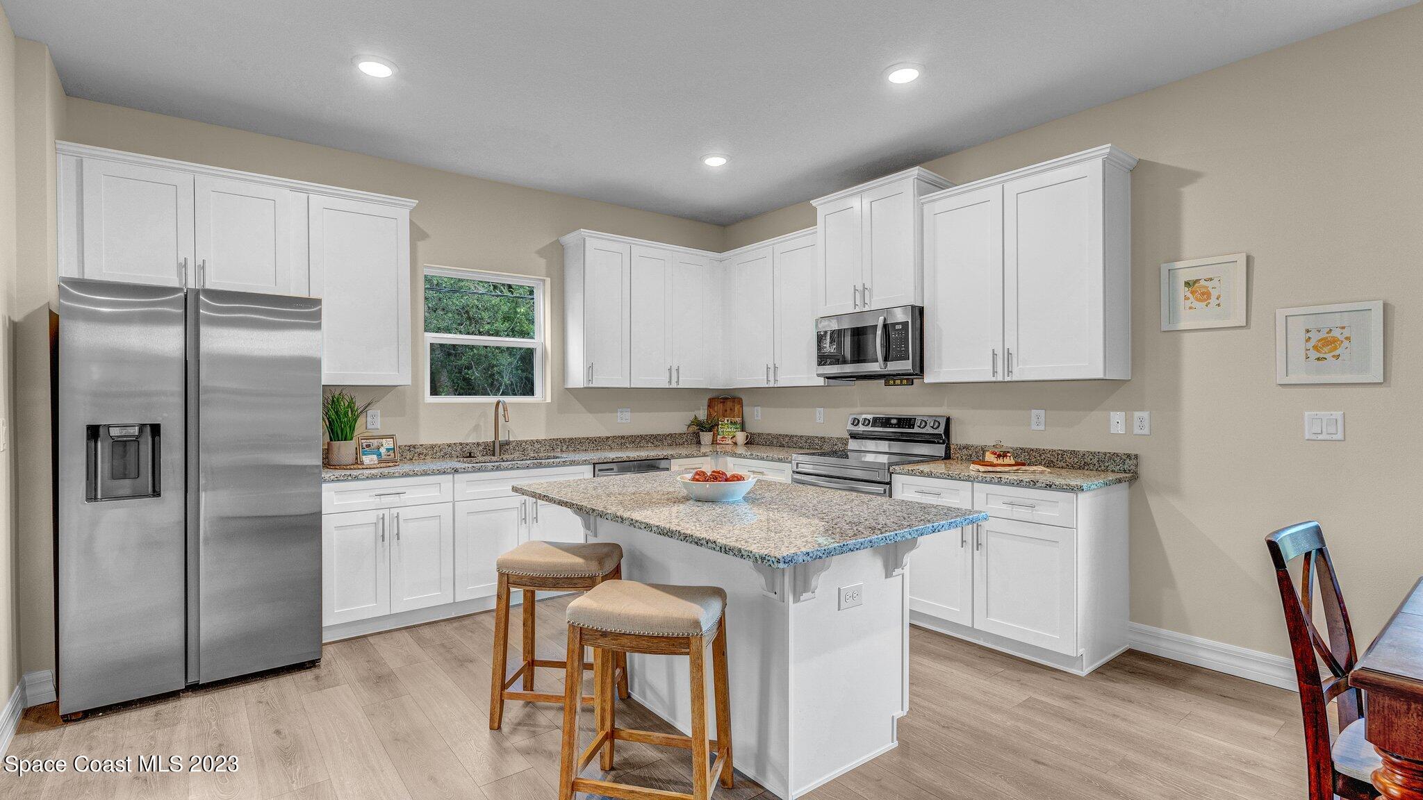 491 Tilhal Road Southwest Palm Bay, FL 32908 - Photo 9 of 30 a kitchen with stainless steel appliances granite countertop a stove a sink a refrigerator a microwave and cabinets