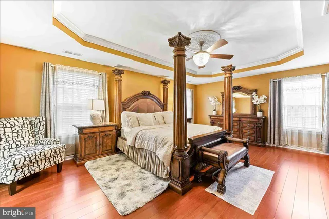 a bedroom with a bed ceiling fan and a wooden floor