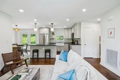 a living room with stainless steel appliances furniture and a kitchen view