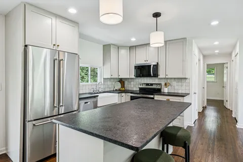 a kitchen with stainless steel appliances granite countertop a refrigerator a stove a microwave oven a sink dishwasher and a refrigerator with wooden floor