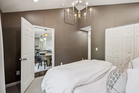 a spacious bedroom with a bed and table chair