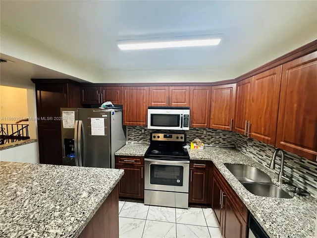 a kitchen with granite countertop wooden cabinets and stainless steel appliances