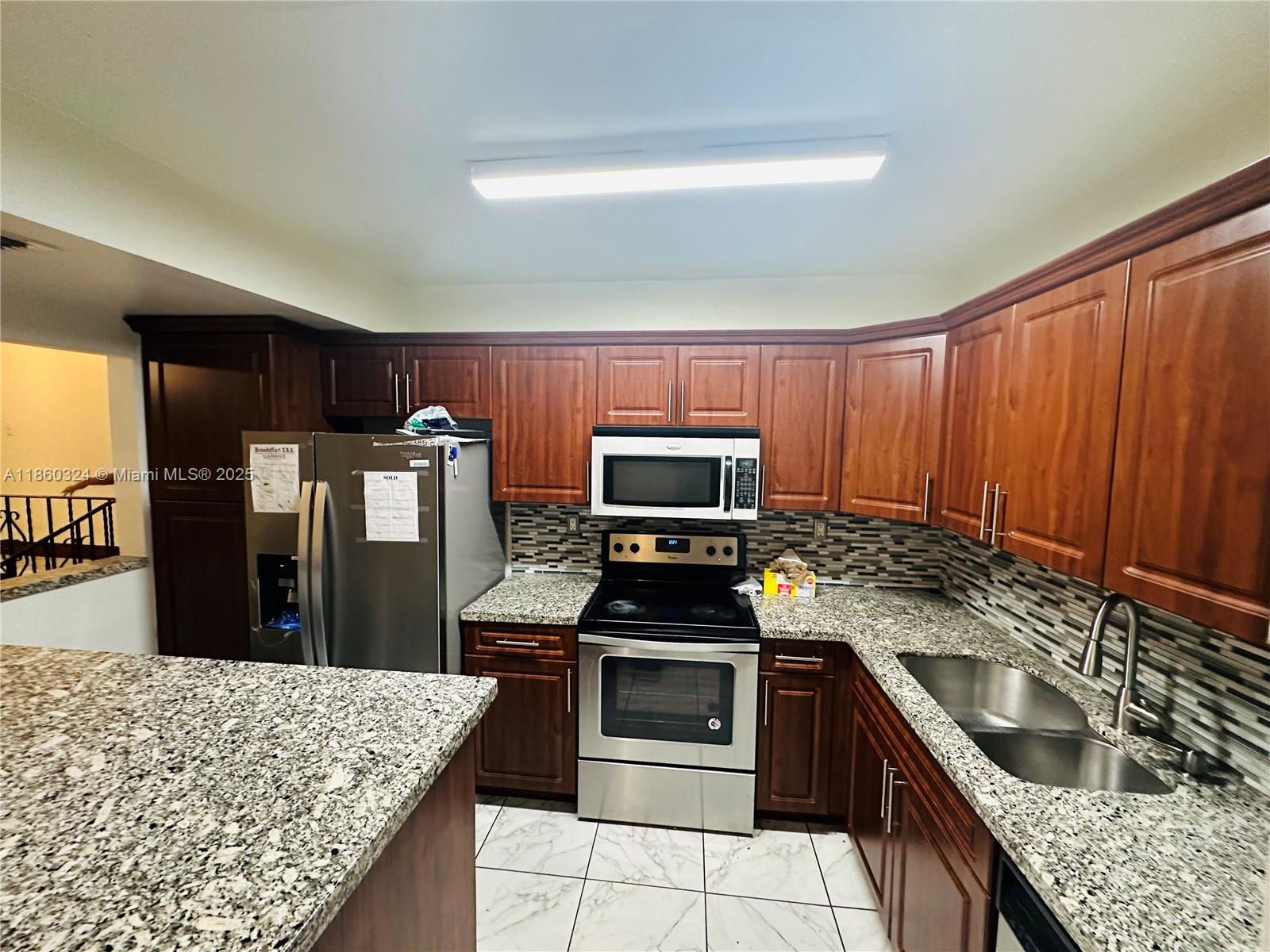 4850 Southwest 63rd Terrace, Unit 323 Davie, FL 33314 - Photo 4 of 12 a kitchen with granite countertop wooden cabinets and stainless steel appliances