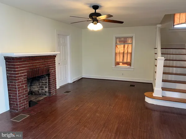 a view of an empty room with wooden floor fireplace and a window