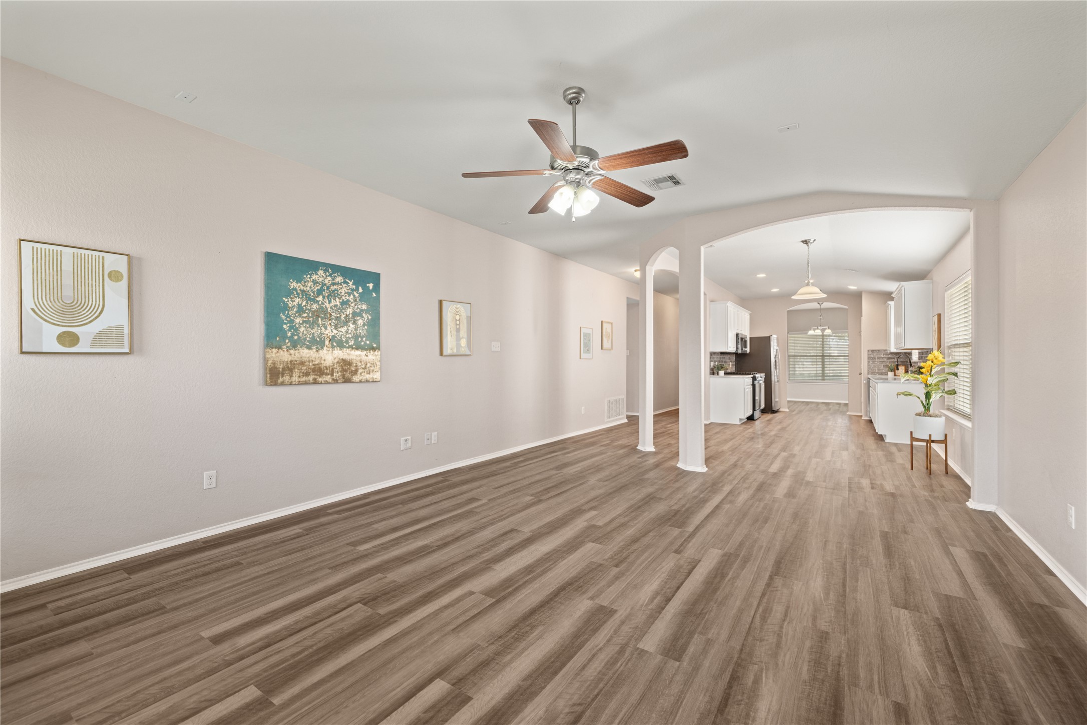20105 Harrier Flight Trail Pflugerville, TX 78660 - Photo 5 of 35 Unfurnished living room with ceiling fan, arched walkways, wood finished floors, and vaulted ceiling