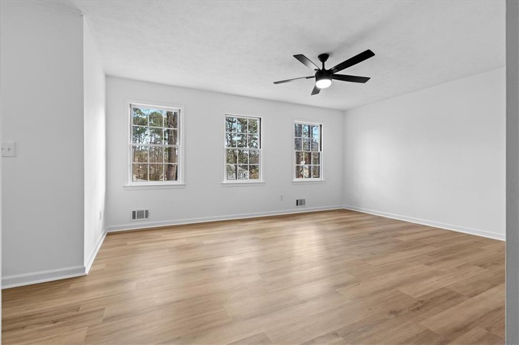 7605 Raleigh Lane Jonesboro, GA 30236 - Photo 27 of 40 an empty room with wooden floor a ceiling fan and windows