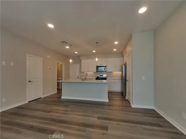 a view of kitchen with kitchen island stainless steel appliances wooden floor and living room view