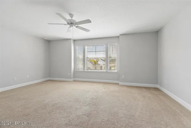 an empty room with window and ceiling fan