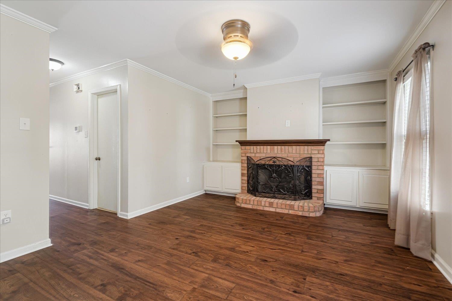 6976 Country Road, Unit 34 Germantown, TN 38138 - Photo 4 of 25 a view of an empty room with wooden floor fire place and a kitchen