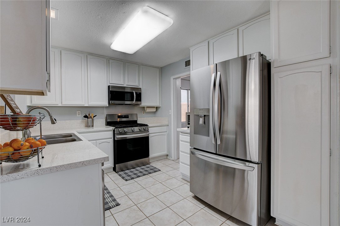 3153 Viewcrest Avenue Henderson, NV 89014 - Photo 12 of 49 Nicely updated kitchen features lots of modern white cabinets, quartz counters, newer Stainless Steel appliances, pantry and easy-care tile flooring.