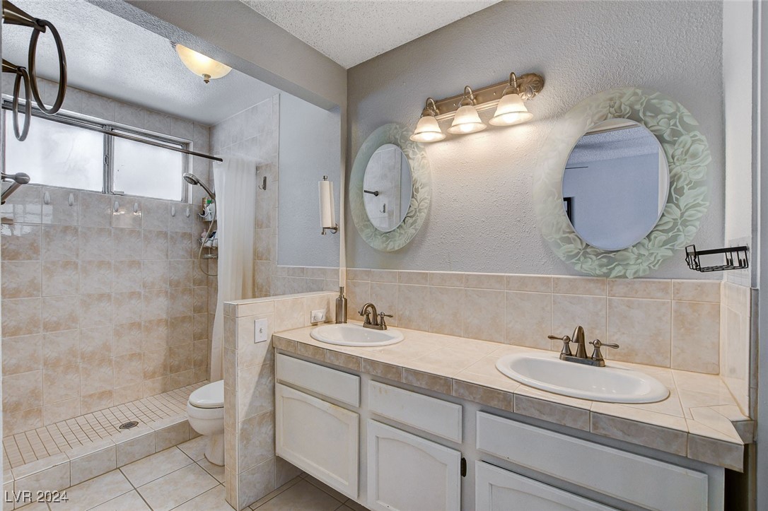 3153 Viewcrest Avenue Henderson, NV 89014 - Photo 27 of 49 Master Bath includes a second mirrored closet, dual sink tiled vanity and coordinating tiled walk-in shower. Note the beautiful etched wall mirrors!