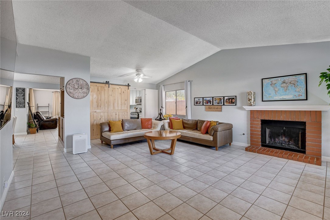 3153 Viewcrest Avenue Henderson, NV 89014 - Photo 6 of 49 Enter from the front door into this spacious, light and bright Living Room with gas fireplace adorned with mantel and brick hearth, vaulted ceiling and barn-door storage area. Note the easy-care tile flooring throughout the home.