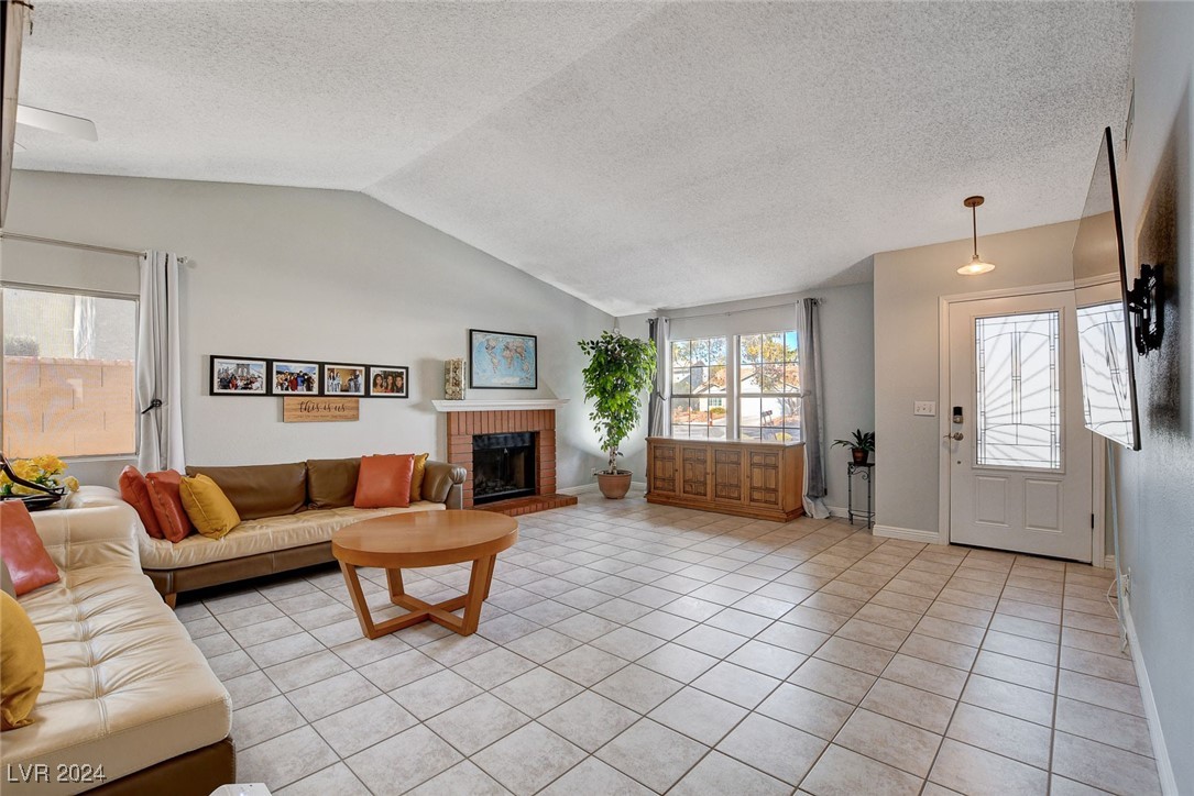 3153 Viewcrest Avenue Henderson, NV 89014 - Photo 7 of 49 Enter from the front door into this spacious, light and bright Living Room with gas fireplace adorned with mantel and brick hearth, vaulted ceiling and barn-door storage area. Note the easy-care tile flooring throughout the home.