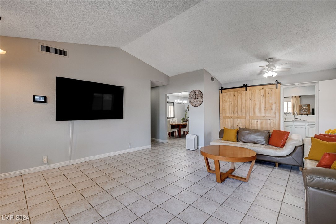 3153 Viewcrest Avenue Henderson, NV 89014 - Photo 9 of 49 Enter from the front door into this spacious, light and bright Living Room with gas fireplace adorned with mantel and brick hearth, vaulted ceiling and barn-door storage area. Note the easy-care tile flooring throughout the home.