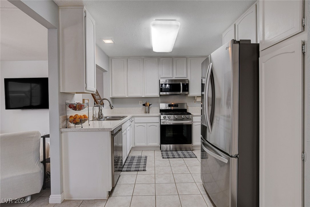 3153 Viewcrest Avenue Henderson, NV 89014 - Photo 10 of 49 Nicely updated kitchen features lots of modern white cabinets, quartz counters, newer Stainless Steel appliances, pantry and easy-care tile flooring.