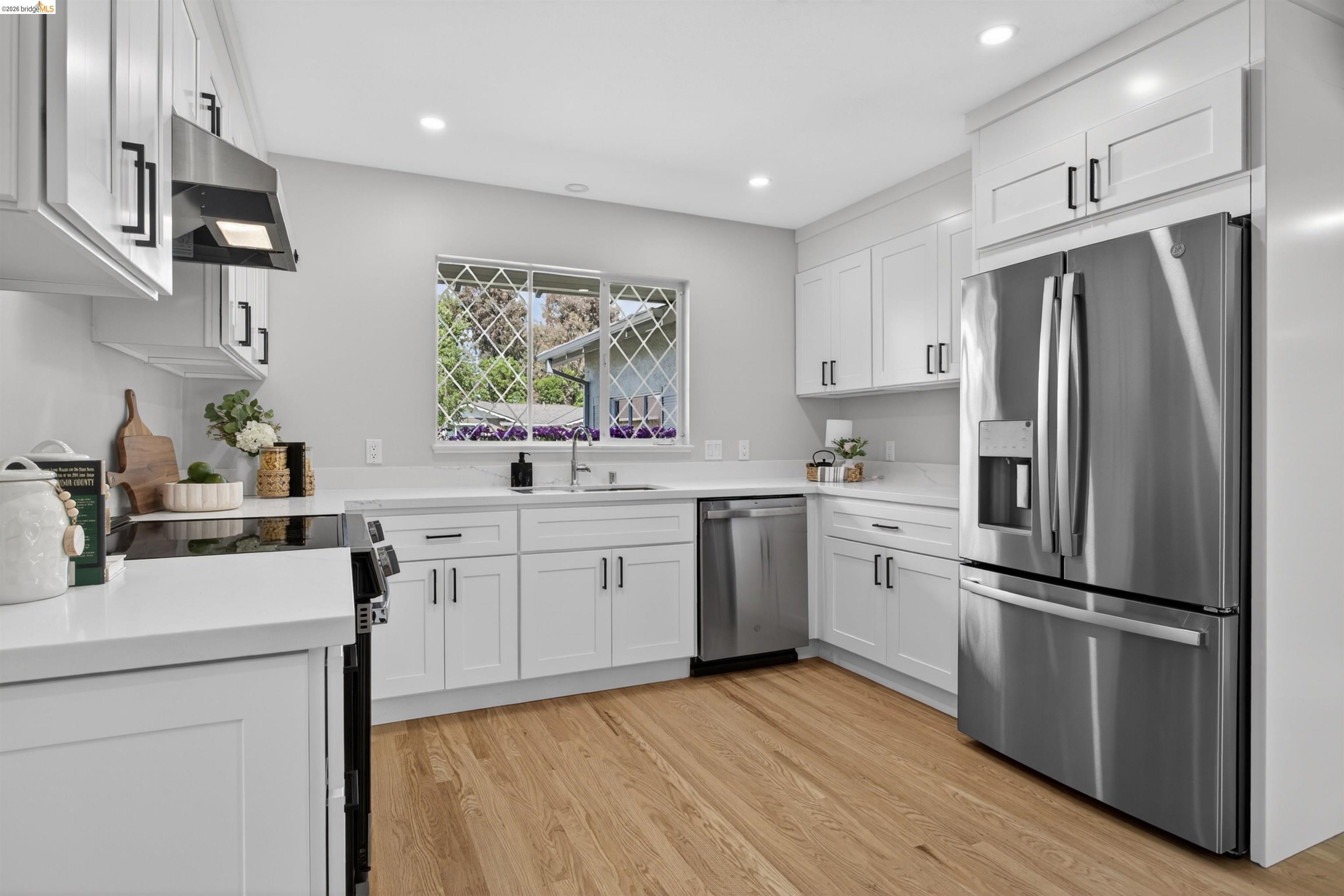 4321 Davis Way Livermore, CA 94550 - Photo 11 of 34 Modern kitchen featuring white shaker cabinetry, stainless steel appliances, light-toned wood-finish flooring, white countertops, and a window with security bars