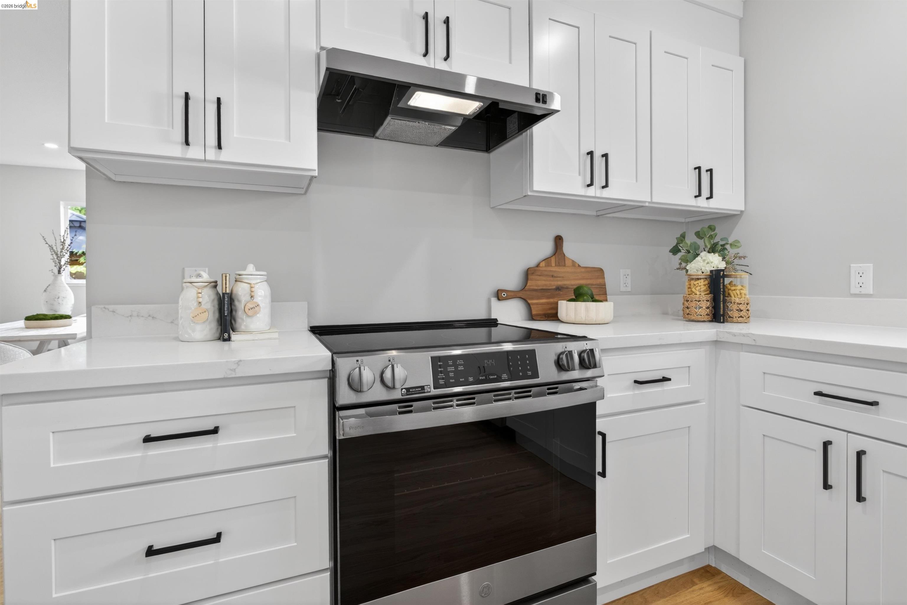 4321 Davis Way Livermore, CA 94550 - Photo 12 of 34 Modern kitchen featuring white shaker cabinetry, stainless steel range with overhead ventilation, and light-toned countertops