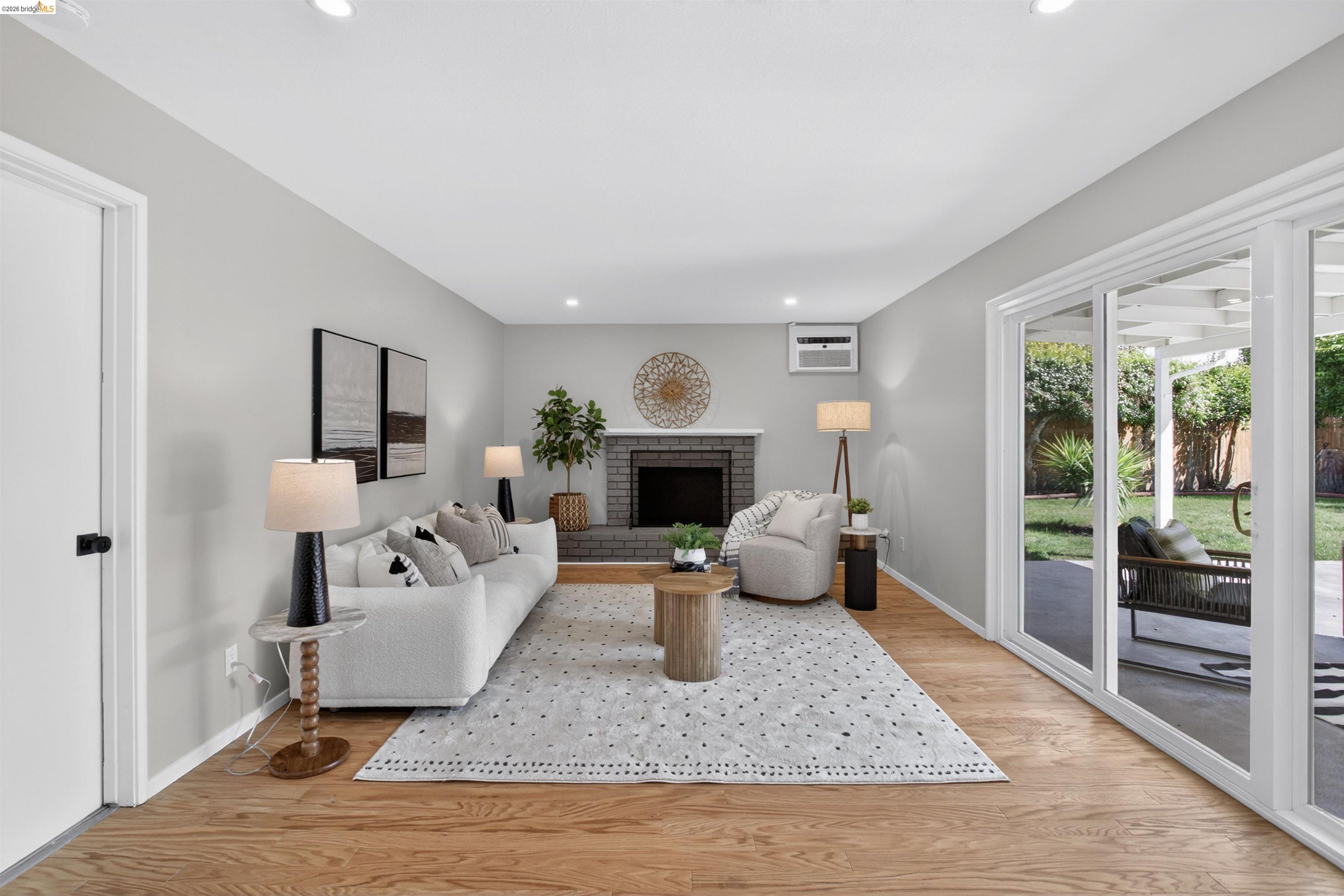 4321 Davis Way Livermore, CA 94550 - Photo 15 of 34 Living room featuring wood-finish flooring, a brick fireplace, recessed lighting, and sliding glass doors opening to a concrete patio and a grassy area