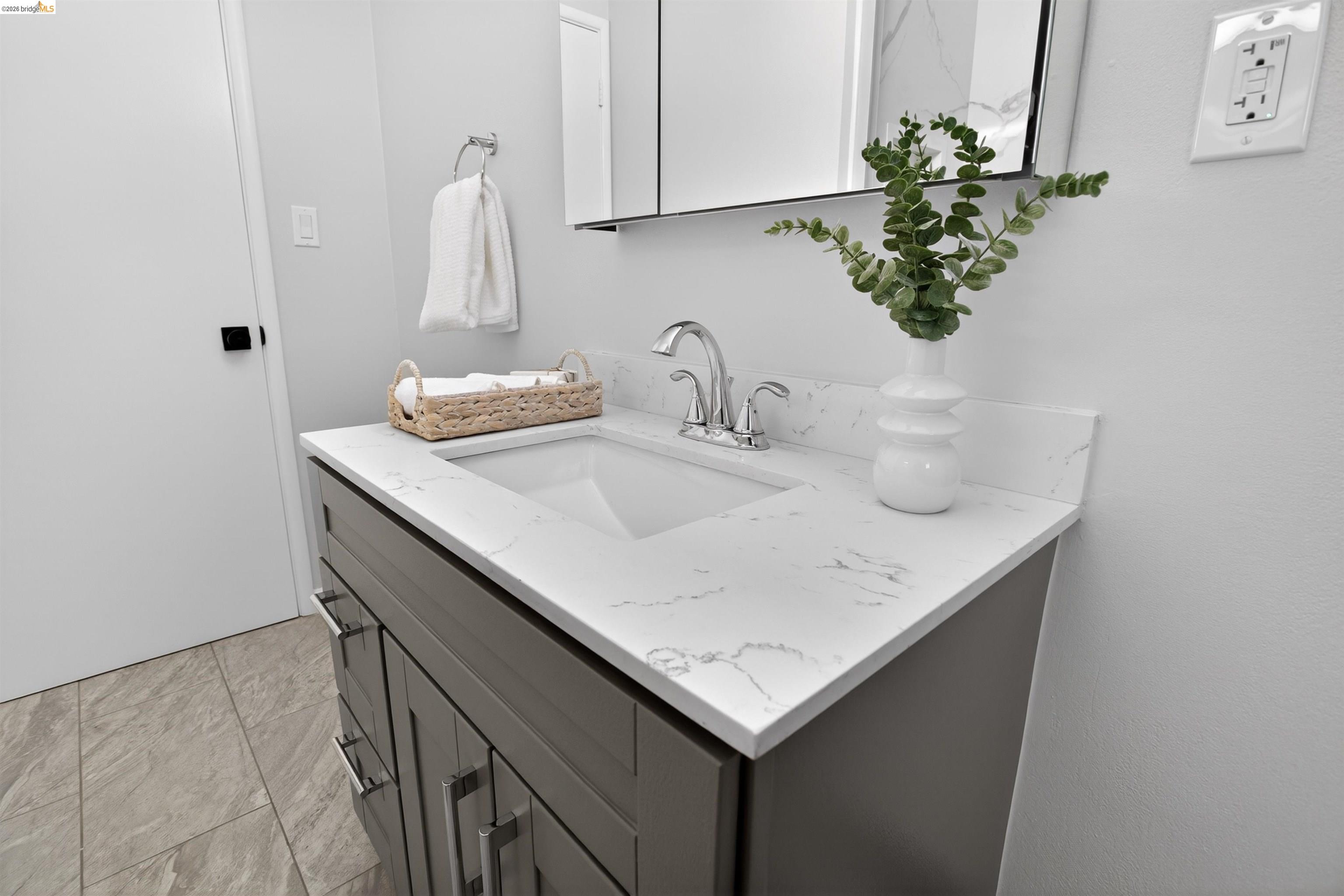 4321 Davis Way Livermore, CA 94550 - Photo 19 of 34 Bathroom vanity featuring a quartz countertop with an integrated sink, chrome faucet, gray cabinetry with metal hardware, and tiled flooring