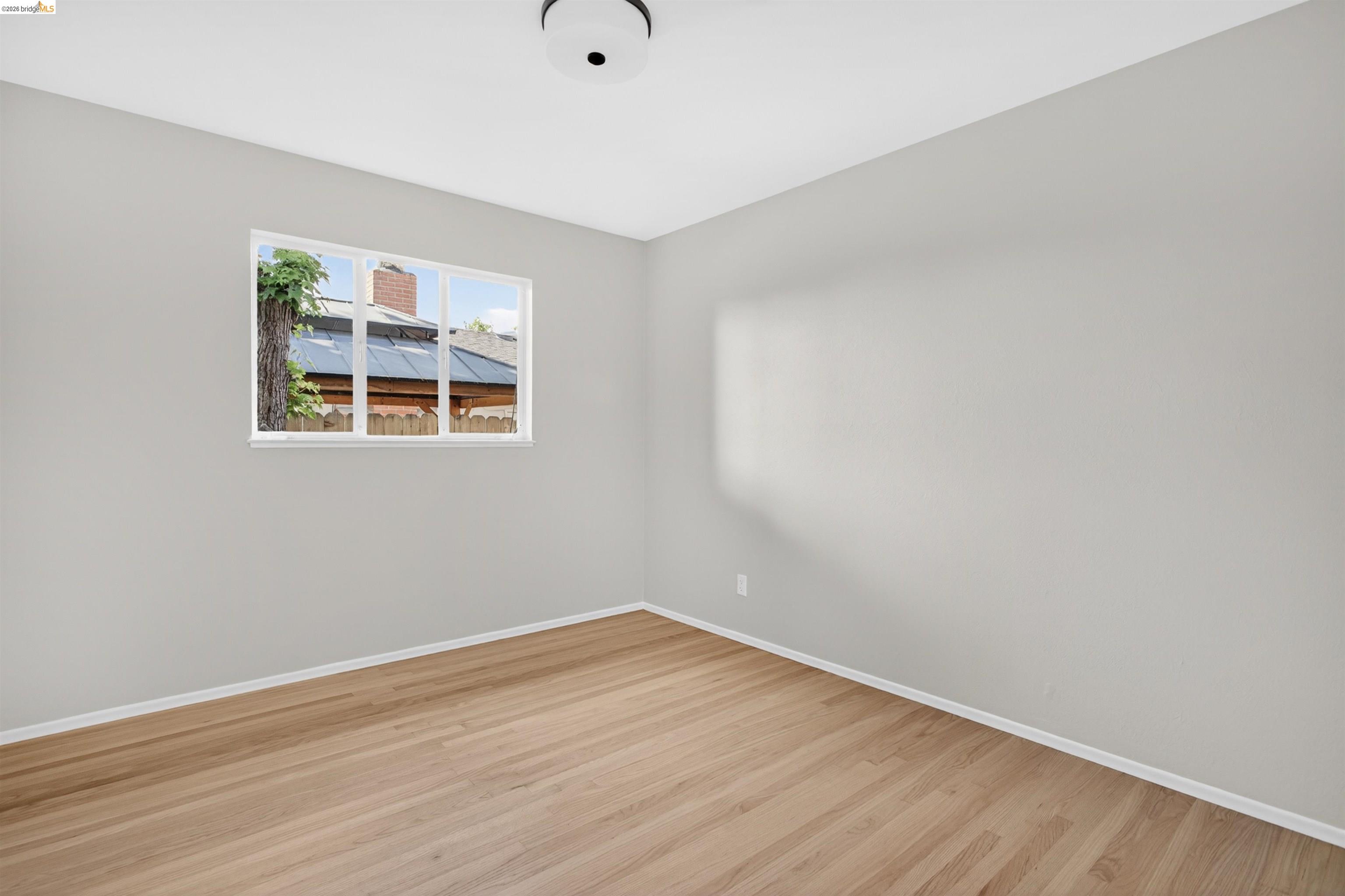 4321 Davis Way Livermore, CA 94550 - Photo 25 of 34 Light-filled room featuring wood-finish flooring, neutral gray walls, white baseboards, a white ceiling, and a flush-mount ceiling light fixture