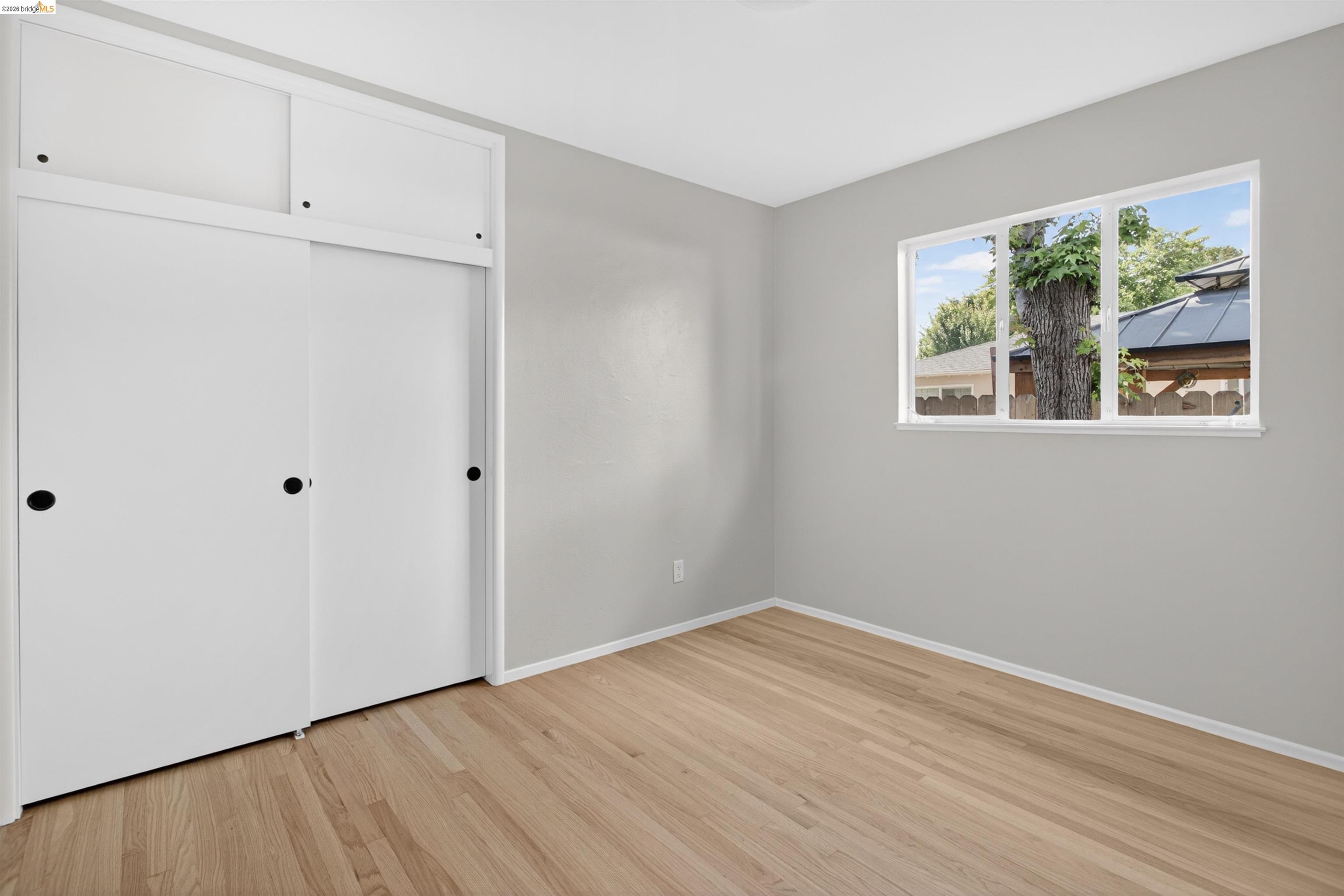 4321 Davis Way Livermore, CA 94550 - Photo 26 of 34 Light-filled room featuring wood-finish flooring, a multi-pane window, and a built-in sliding door closet with upper cabinetry
