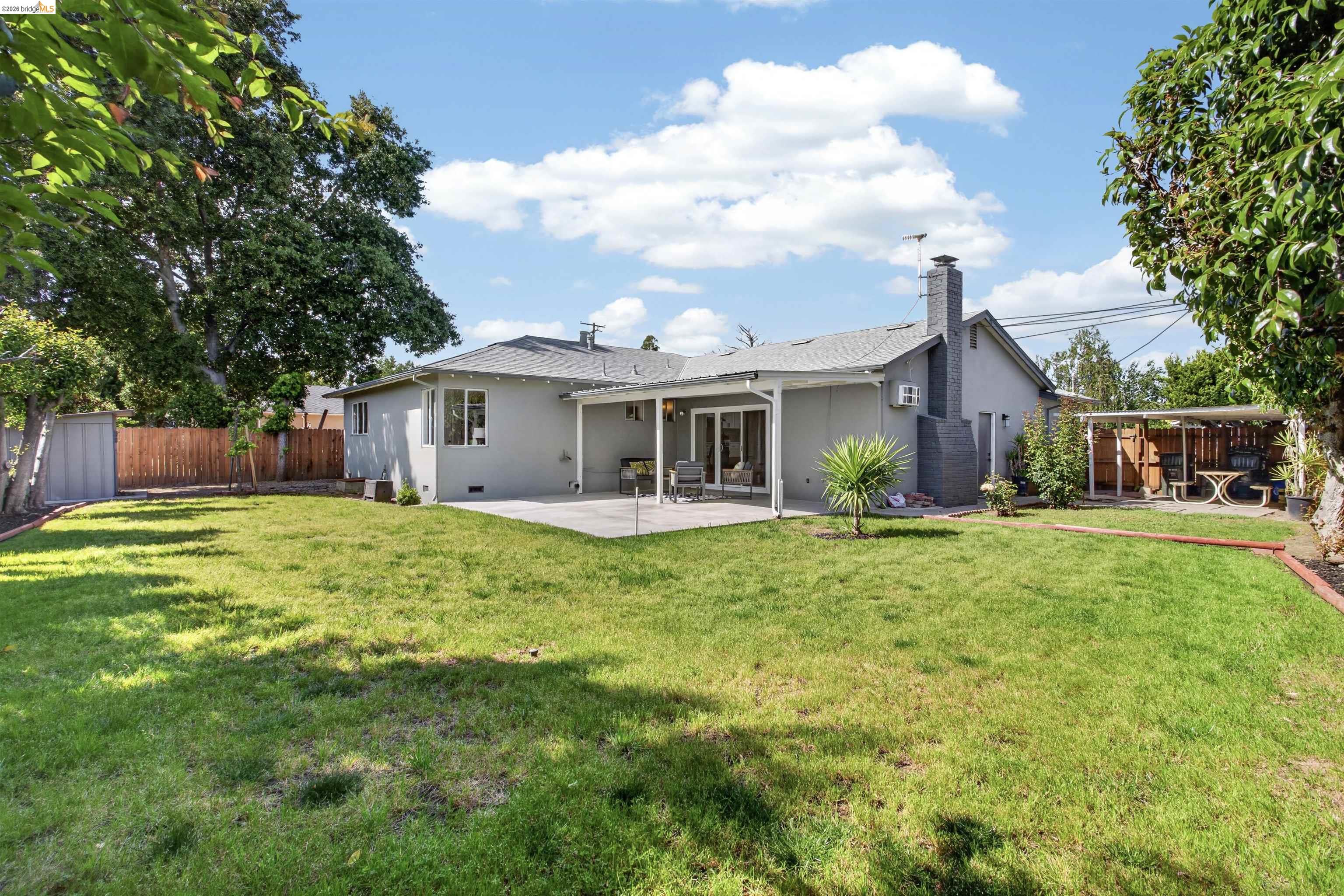 4321 Davis Way Livermore, CA 94550 - Photo 30 of 34 Expansive backyard featuring a large grass area, mature perimeter trees, and a concrete patio
