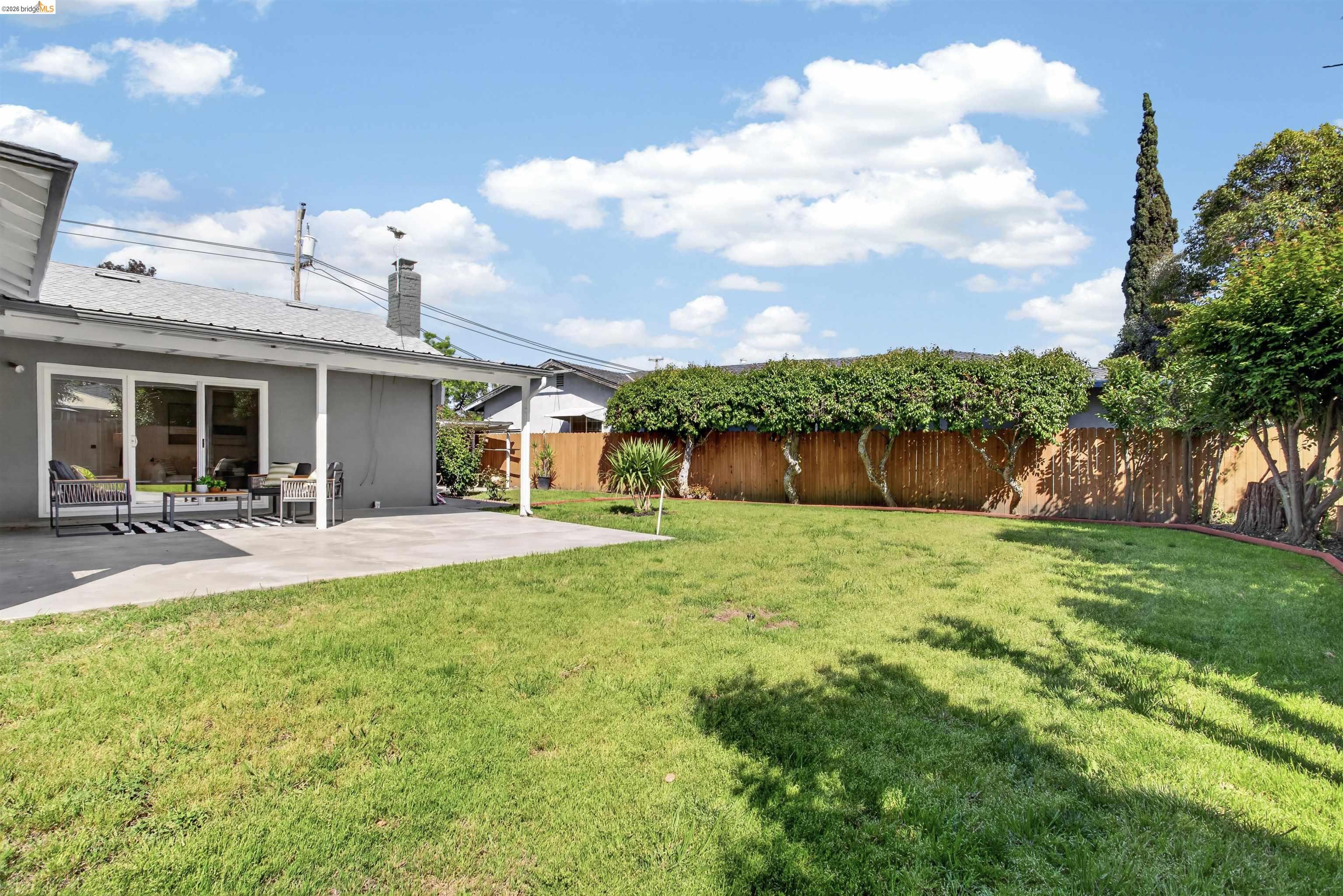 4321 Davis Way Livermore, CA 94550 - Photo 33 of 34 Expansive backyard featuring a manicured lawn, concrete patio, and mature perimeter trees