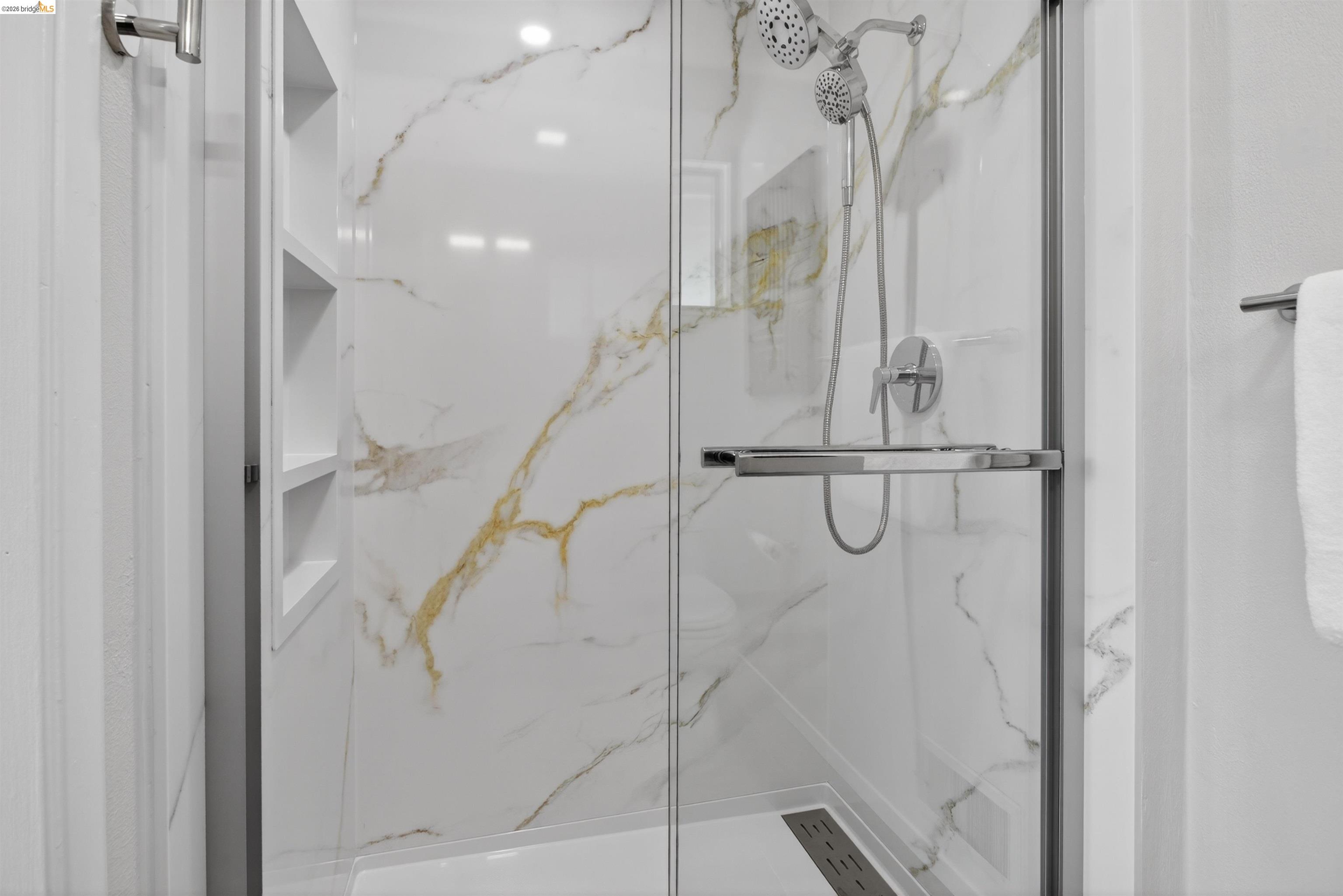 4321 Davis Way Livermore, CA 94550 - Photo 34 of 34 Frameless glass shower enclosure featuring white and gold veined wall panels, a multi-function showerhead, built-in shelving, and a linear shower drain